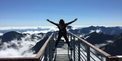 Woman at top of mountain celebrating after overcoming life's hurdles